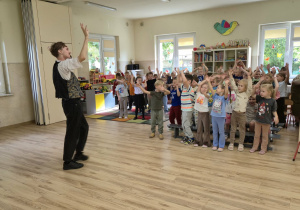 Dzieci na sali gimnastycznej naśladują taniec pokazany przez muzyka