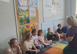 Dzieci siedzą w kole podczas warsztatów z panią psycholog.