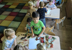 Dzieci przy stolikach układają obrazy z darów jesieni