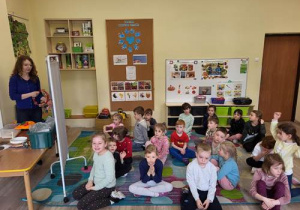 Wszystkie dzieci siedzą na dywanie i nasłuchują dźwięków instrumentów.
