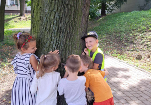 Dzieci przytulają się do drzewa.
