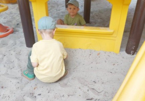 Chłopcy bawią się w piasku.