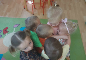 Dzieci przytulają dziewczynkę.