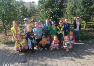 Grupa dzieci przy jabłoniach.