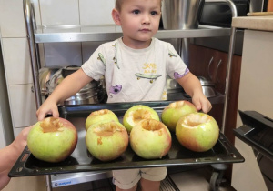 Chlopiec prezentuje przygotowane jabłka do pieczenia.