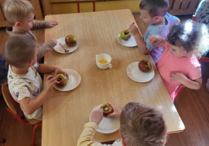 Dzieci degustują pieczone jabłka.