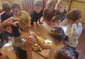Dzieci wykonują sok z jabłek z wykorzystaniem sokowirówki.