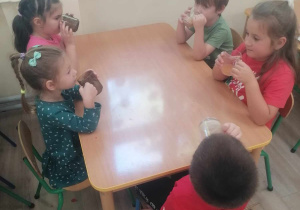 Dzieci piją sok jabłkowy.