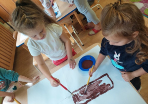 Dzieci malują farbami jesienne drzewo.