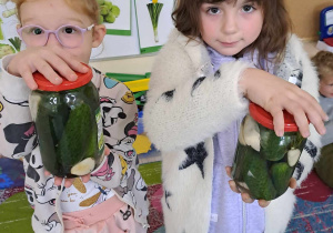 Dwie dziewczynki trzymają słoiki z ogórkami