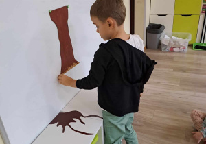 Chłopiec przypina elementy drzewa do tablicy.
