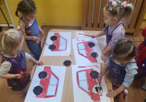 Dzieci malują farbami plakatowymi sylwety auta z wykorzystaniem 2 kolorów.