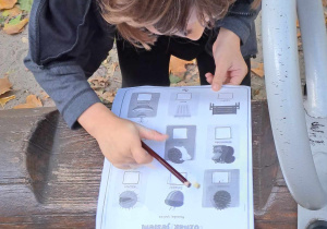 Chłopiec zapisuje na kartce ilość znalezionych przedmiotów