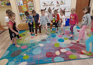 Dzieci ćwiczą boso na dywanie.