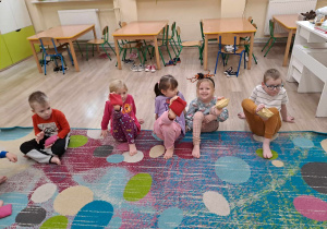 Dzieci ćwiczą boso na dywanie.