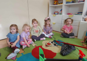 Dzieci siedzą na dywanie podczas zajęć.