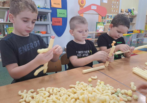 Dzieci tworzą pracę przestrzenną z chrupek kukurydzianych.