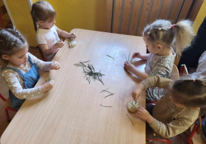 Dzieci wbijają igły z sosny w uformowanego jeża.
