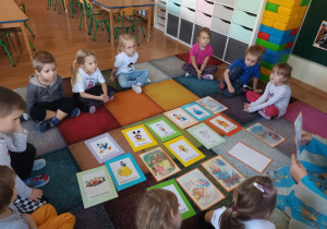 Dzieci oglądają ilustracje przedstawiające postaci z różnych bajek.