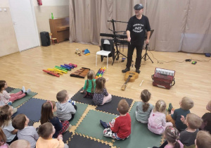 Pan zapoznaje dzieci z instrumentami muzycznymi.