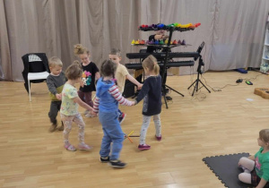 Dzieci tańczą w kole do granej muzyki.