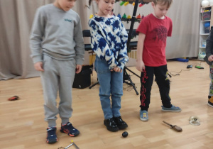 Troje dzieci stoi przy instrumentach muzycznych