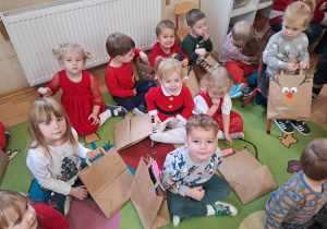 Dzieci siedzą na dywanie z prezentami