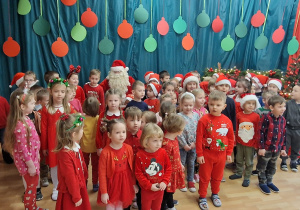 Dzieci pozują na tle dekoracji z Mikołajem