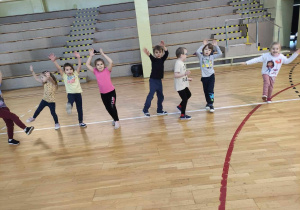 Dzieci ćwiczą na sali gimnastycznej.