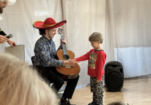 Chłopiec liczy struny w gitarze.