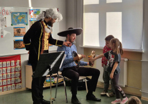 Dzieci pomagają muzykowi złożyć waltornię