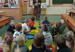 Dzieci słuchają opowiadania nauczycielki.