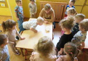 Dzieci eksperymentując odpowiadają na pytanie - "Co zrobić, żeby kulka waty znalazła się na podłodze, bez użycia rąk?