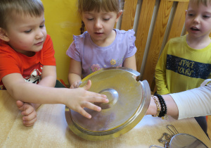 Dzieci obsernują zjawisko osadzania się pary na pokrywce garnka podczas gotowania.