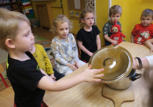 Dzieci obsernują zjawisko osadzania się pary na pokrywce garnka podczas gotowania.