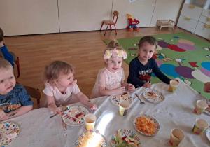 Dzieci jedzą tort oraz przygotowane smakołyki.