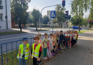 Dzieci pozują na tle ruchliwej drogi.