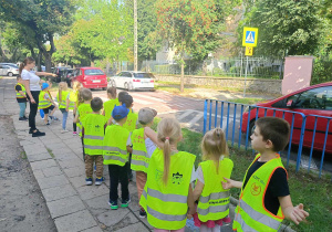 Nauczycielka przypomina dzieciom, jak należy zachować się przed przejściem dla pieszych.