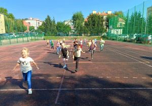 Dzieci grają w piłkę nożną na boisku szkolnym.