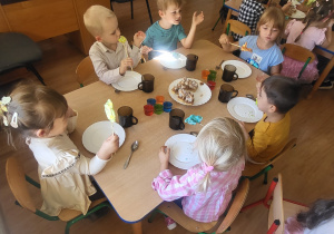 Dzieciaki zajadają słodkie bezowe lizaki.