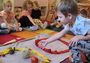 Oliwier wkłada kuliste warzywo do odpowiedniej pętli.