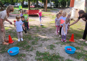 Dzieci w trakcie zabawy z elementem rzutu "Wrzuć pomidora do miski".