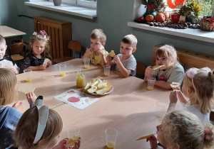 Dzieci jedzą wafelki i jabłka.