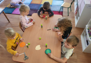 Dzieci wykonują swoje ulubione owoce z materiału plastycznego.