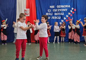 Dwóch chłopców wykonuje choreografię do muzyki klasycznej.