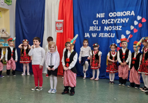 Troje dzieci recytuje wiersze do mikrofonu.