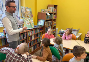 Pan bibliotekarz pokazuje dzieciom książkę 3D z dzieciny anatomii.