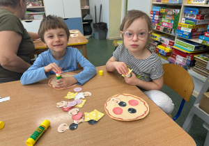 Dzieci układają zakupione produkty na pizzy.