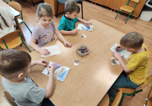 Dzieci kolorują kartkę barwami jakie kojarzą się ze smutkiem.