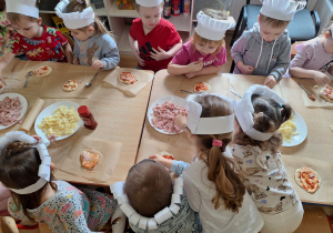 dzieci nakładają różne składniki na pizze